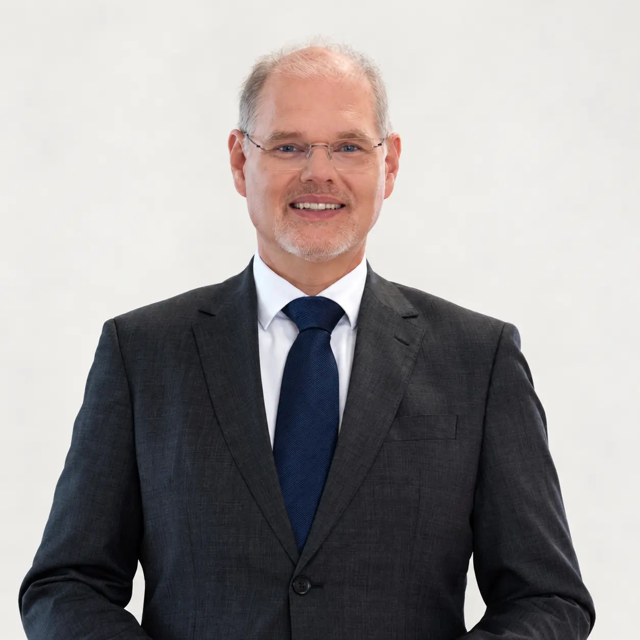 Franz Öller im dunklen Anzug vor einem hellen Hintergrund